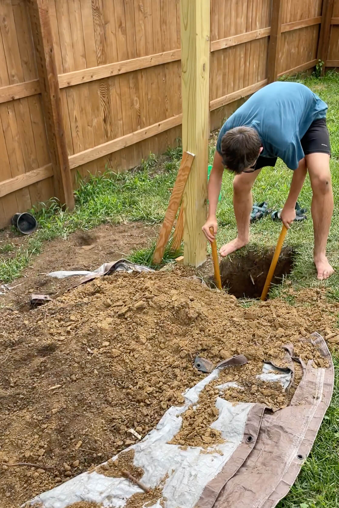 Using a post hole digger to dig a hole in the backyard.